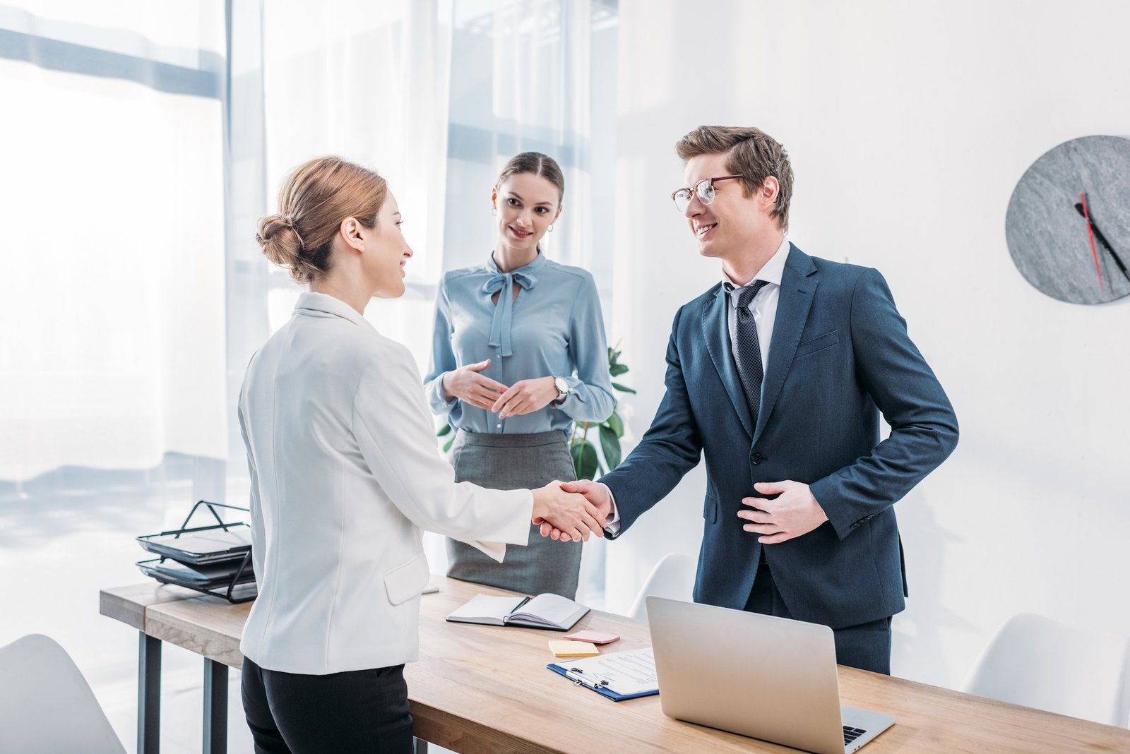 cheerful-recruiter-shaking-hands-with-woman-near-colleague-in-office.jpg
